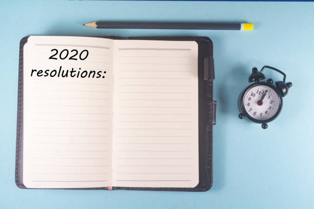 istock Pencil, notebook with 2020 resolutions and alarm clock 1195938999