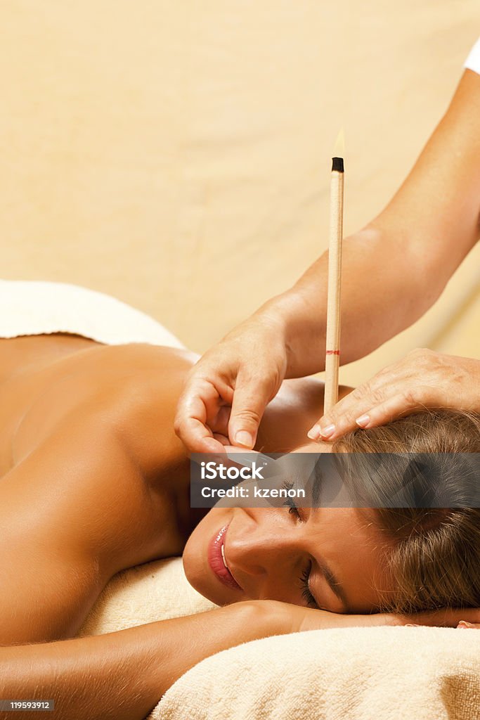 A young woman getting ear candle therapy Woman in wellness and spa setting having with ear candles and gem massage Ear Candling Stock Photo
