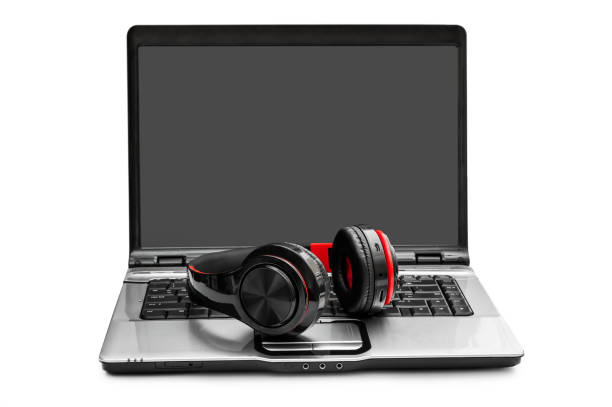 A laptop with charging headphones on top