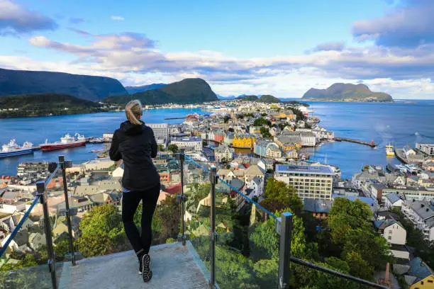 Blond woman enjoying aerial view of the colorful art nouveau town of Alesund Norway