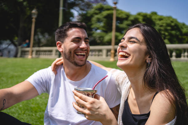 istock Couple drinking yerba mate and joking around while sitting on grass 1195943844