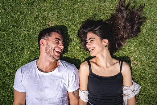 Young couple lying down on a grass area together bonding