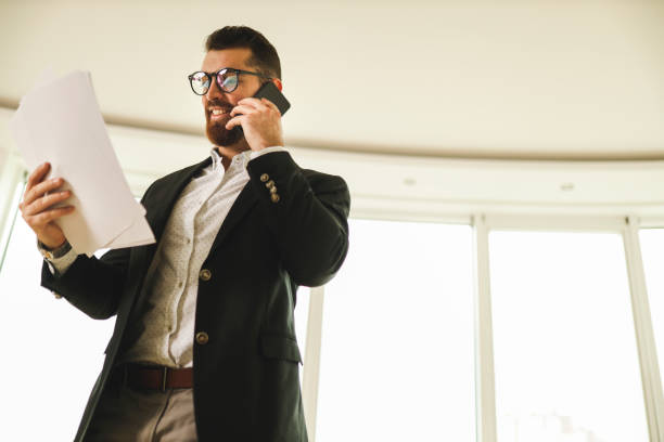 istock Businessman using smart phone and holding contracts 1195946569