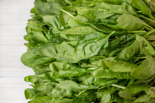 istock Spinach leaves on a wooden white table. 1195946654
