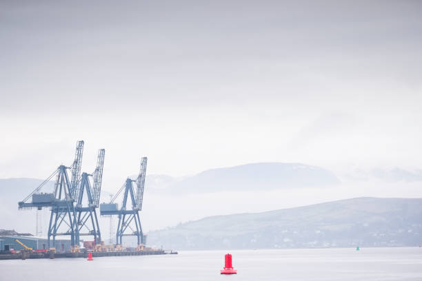 istock Container terminal crane gantry for loading and offloading cargo freight shipping at quay yard harbour dock on sea coast 1195950736