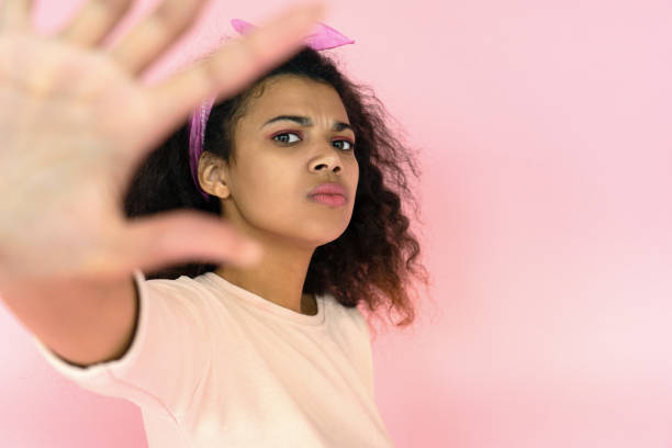 mirada de chica africana molesta en la cámara mostrar stop gesto de la mano en el fondo rosa - african descent addiction african ethnicity rudeness fotografías e imágenes de stock