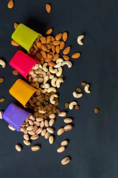 Photo of Healthy Mix Dry Fruits and Nuts on dark background. Almonds, Pistachio, Cashews, Raisins