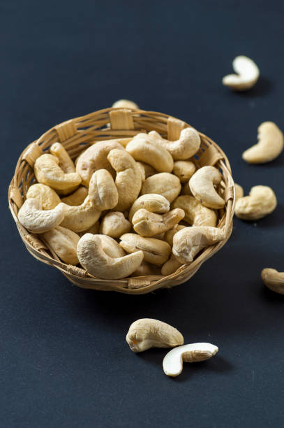 cashew-nüsse im korb auf schwarzem hintergrund - cashewnuss stock-fotos und bilder