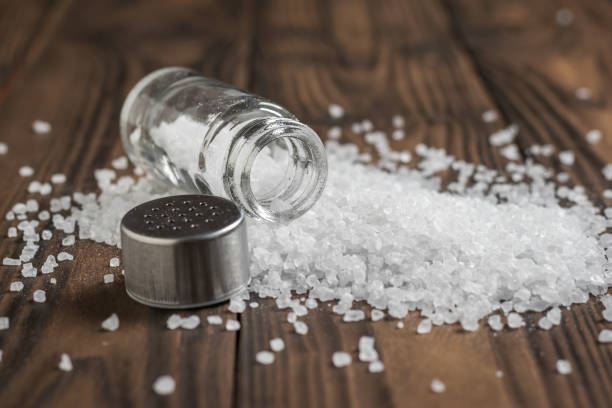 istock Large sea salt scattered on a wooden table. 1195966327