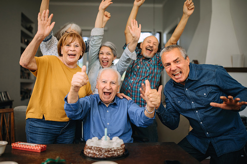 Senior man celebrating birthday with friends in nursing home