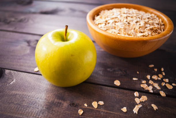 istock Oat flakes in bowl and one apple 1195970513