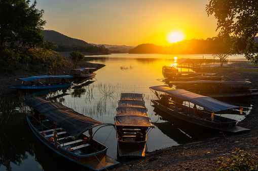 Travelling boats parking on reservoir during sunset in rural of Thailand