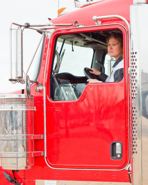 motorista de caminhão da mulher que olha para fora a janela ao conduzir um equipamento grande - empreendedor dentro de seu caminhão - fotografias e filmes do acervo