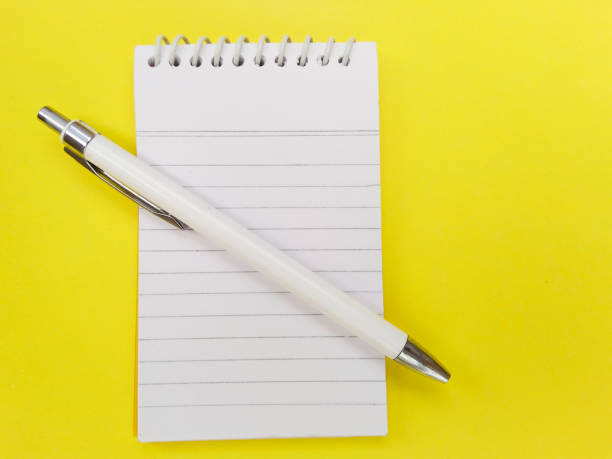 istock Spiral notepad diary and pen isolated on yellow colored background. 1195984307