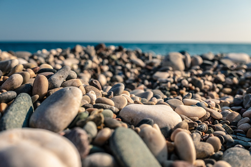 beach with sea pebbles close up on blue sky background. The concept: joy, happiness, positivity, relax, vacation, tourism.