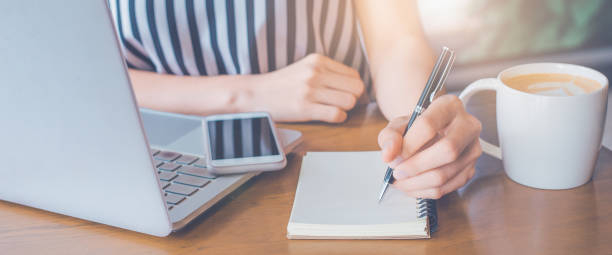 istock business woman working at a computer and writing on a notepad with a pen. 1195994622