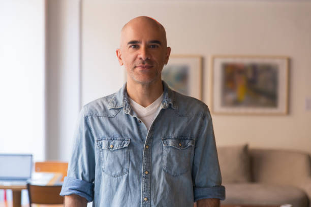 istock Front view of handsome serious bald man posing at home 1195996738
