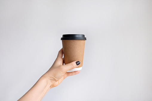 Female hand holding a coffee paper cup isolated on white background.