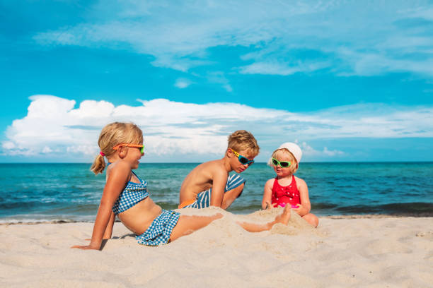 kinder- jungen und mädchen- spielen mit sand am strand - lifestyles child beach digging stock-fotos und bilder