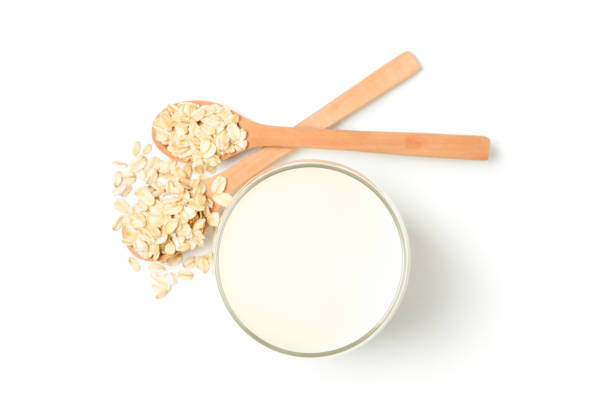lait d'avoine et oatmeels dans la cuillère d'isolement sur le fond blanc. vue du haut - oat oatmeal isolated stack photos et images de collection