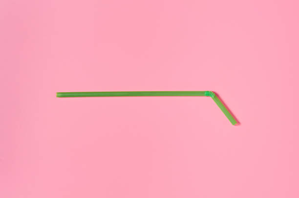 istock One green straw for beverage on pink table. Close-up 1196005526