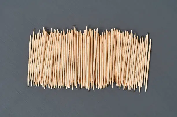 Photo of Row of wooden toothpicks lies on black concrete desk on kitchen. Close-up