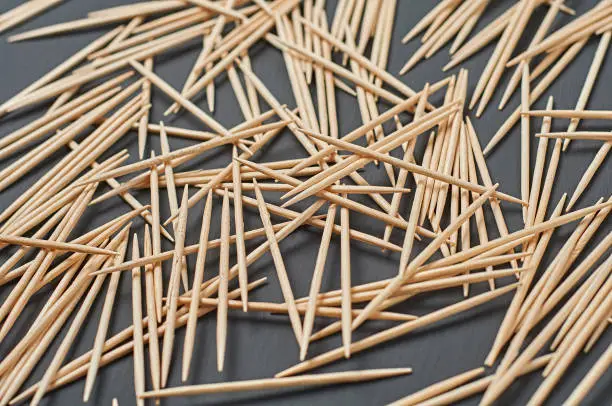 Photo of Scattered wooden toothpicks lies on black concrete desk on kitchen. Close-up