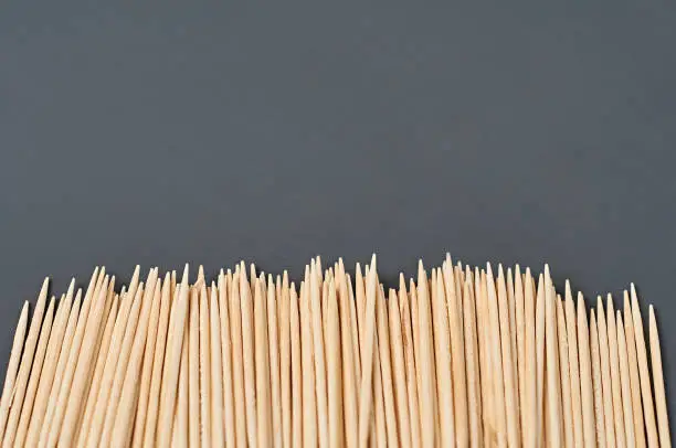 Photo of Row of wooden toothpicks lies on black concrete desk on kitchen. Space for text