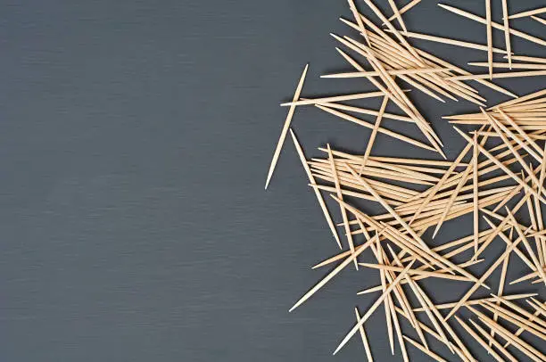 Photo of Scattered wooden toothpicks lies on black concrete desk on kitchen. Space for text. Top view