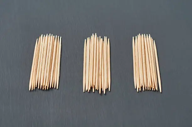 Photo of Three heaps of wooden toothpicks lies on black concrete desk on kitchen. Close-up