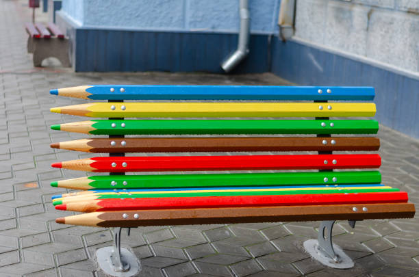 Bright multi-colored street design. Empty bench with raindrops on a city street. Cloudy rainy day. Without people. Soft focus.