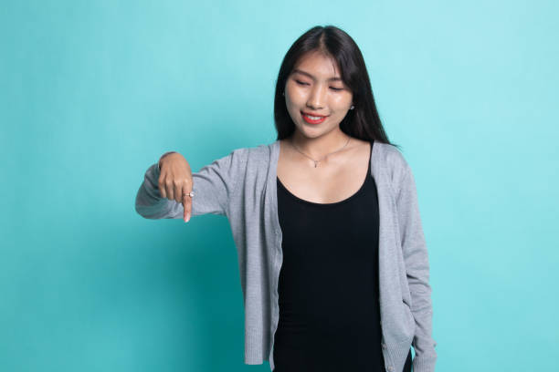 istock Beautiful young Asian woman point down to blank space. 1196006690