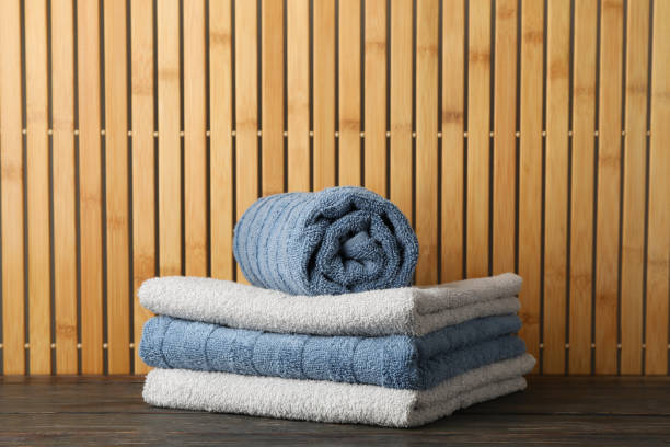 istock Folded towels on wooden table against bamboo background, space for text 1196006867