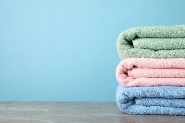 istock Stack of color towels on grey table against blue background, space for text 1196007516
