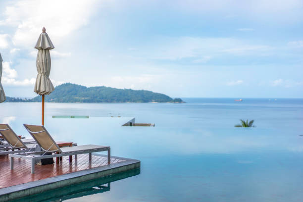 istock Deck chairs and infinity swimming pool with beautiful sea view. 1196007790