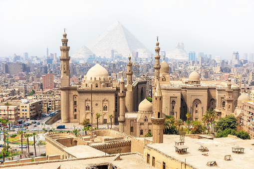Mosque-Madrassa of Sultan Hassan and the Pyramids in the mist, Cairo, Egypt.