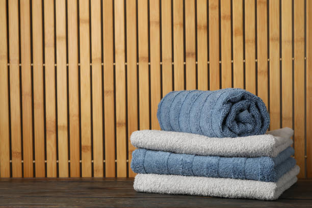 istock Folded towels on wooden table against bamboo background, space for text 1196008555