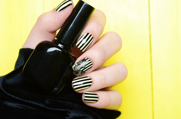istock Bright yellow manicure with black stripes and sunflowers pattern on yellow background 1196015316
