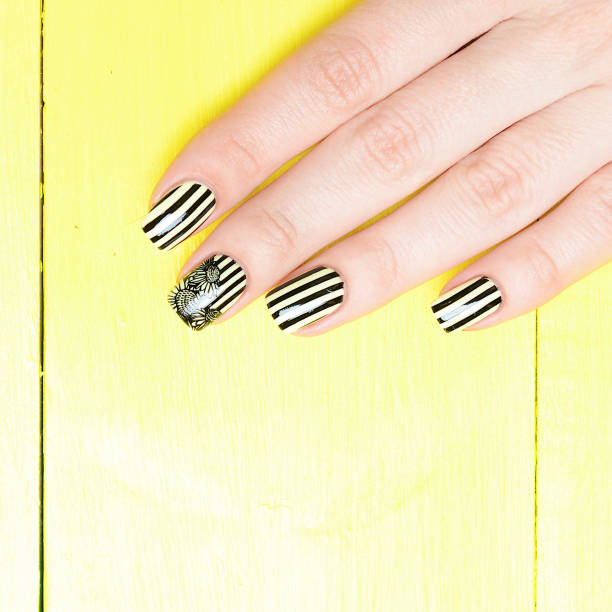 istock Bright yellow manicure with black stripes and sunflowers pattern on yellow background 1196015391
