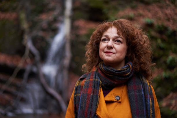istock Woman in yellow coat by a waterfall 1196015414