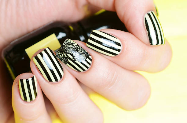 istock Bright yellow manicure with black stripes and sunflowers pattern on yellow background 1196015437