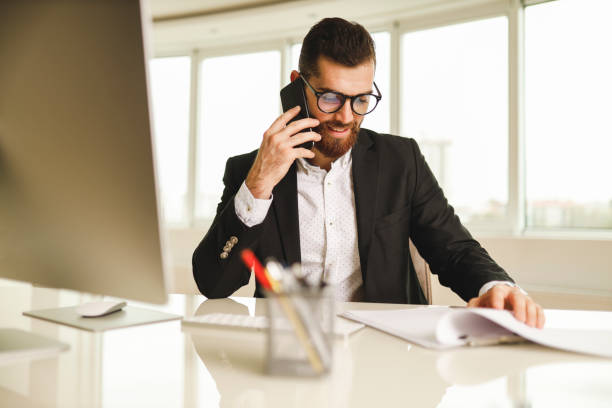 istock Businessman speaking on smart phone and checking contracts 1196016435