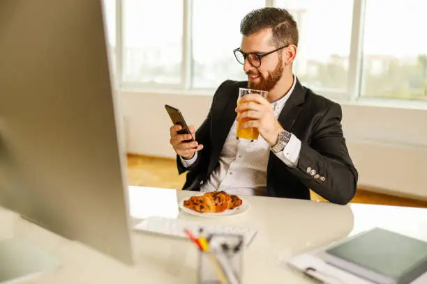 Photo of Businessman using smart phone and drinking juice