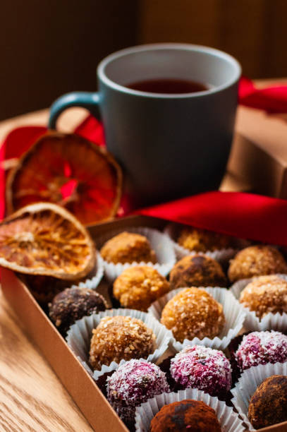 Chocolate Truffles And A Cup Of Tea. A cup of tea and various chocolate truffles in a box for sweets on Christmas evening. chocolate truffle making stock pictures, royalty-free photos & images