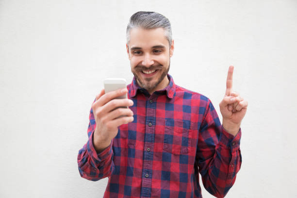 istock Content man with smartphone pointing up with finger 1196020060