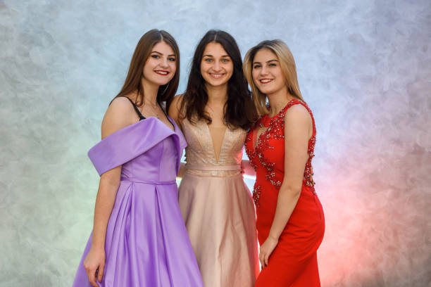 istock Three happy girls in elegant dresses posing on abstract background. Celebration concept 1196023048