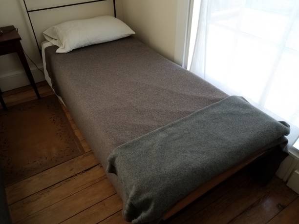 istock small narrow old bed with grey and black blankets 1196028033