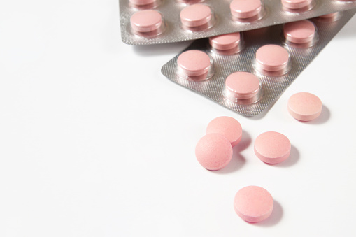 Close up pink colored pills in blister packs on white background