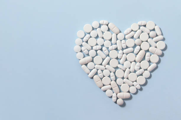 istock Heart Shaped White Pills on Blue Background 1196028850