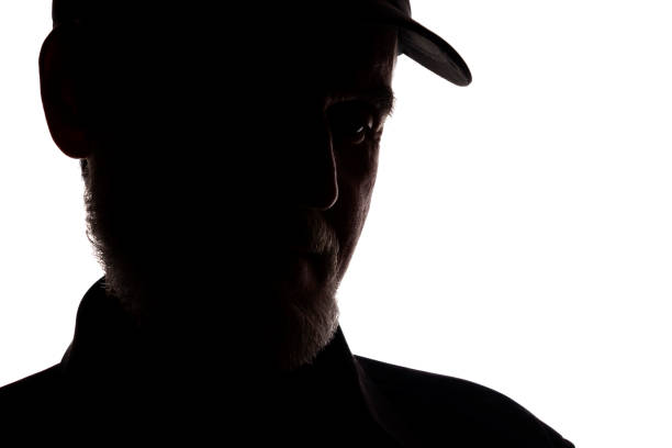istock Old man in peaked cap, side view - dark close-up silhouette 1196033204